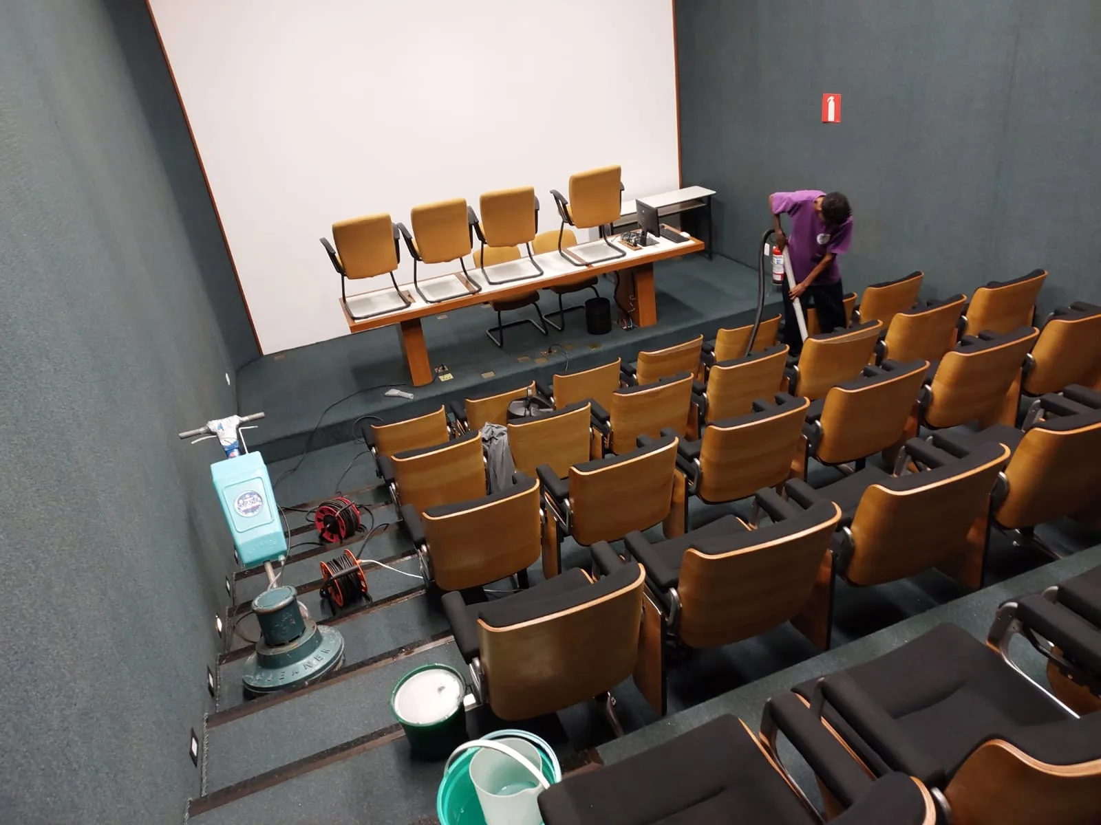 Profissional da Railimp trabalhando entre as poltronas de um auditório