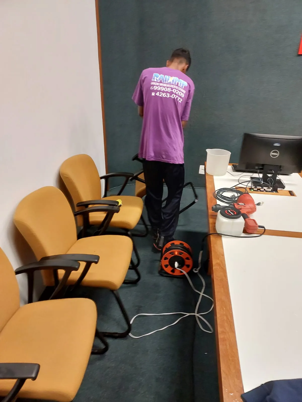 Profissional da Railimp atendendo cadeiras estofadas em sala corporativa